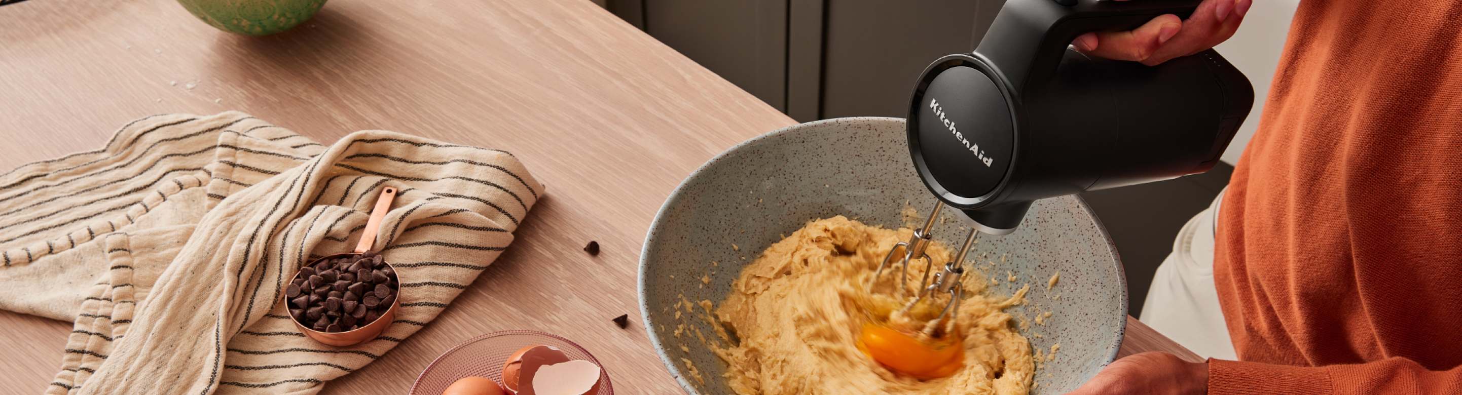A person using the KitchenAid Go™ Cordless Hand Mixer to mix cookie dough.