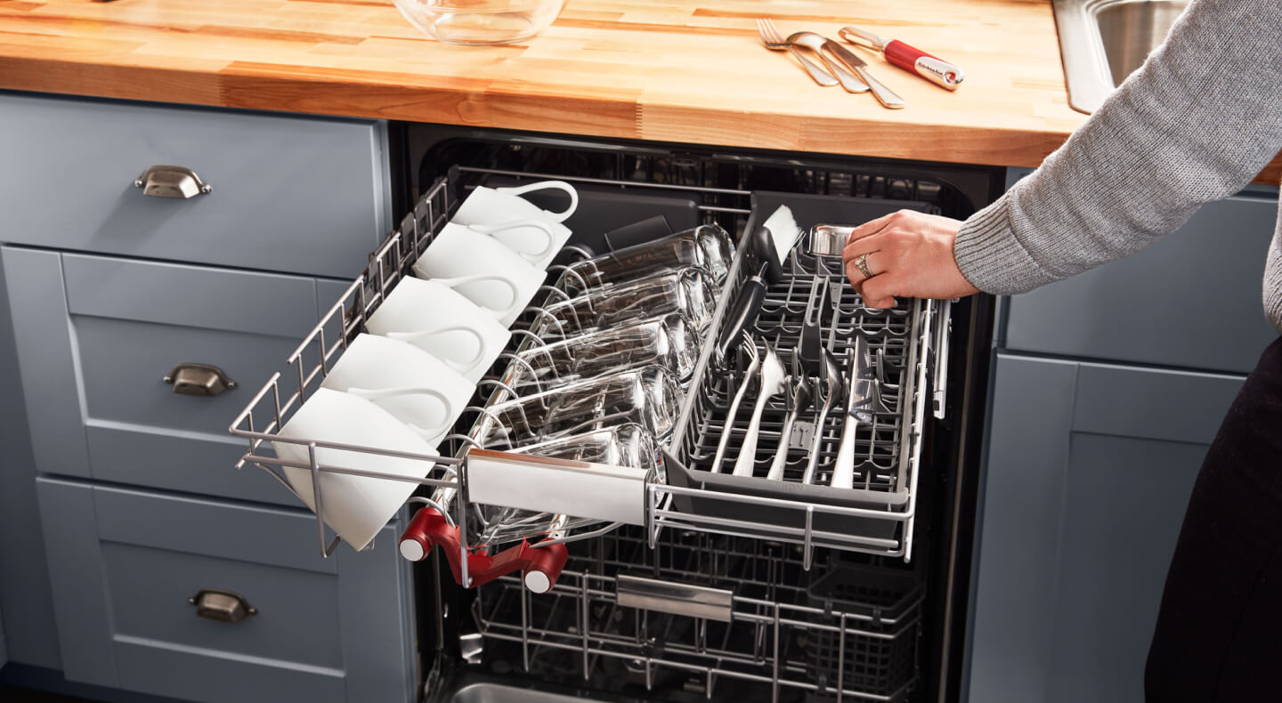 Person loading silverware into a dishwasher’s third rack