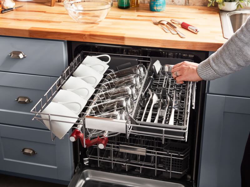 Person loading silverware into a dishwasher’s third rack