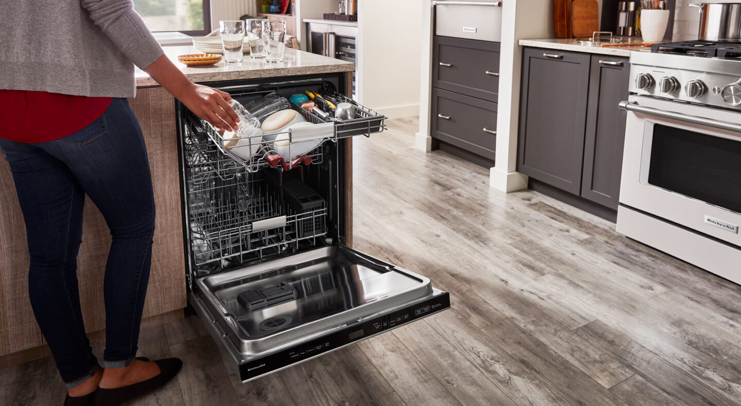 Person loading coffee mugs into a KitchenAid® Third Rack Dishwasher