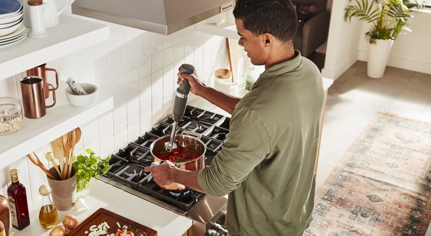 Person using immersion blender in pot on stove