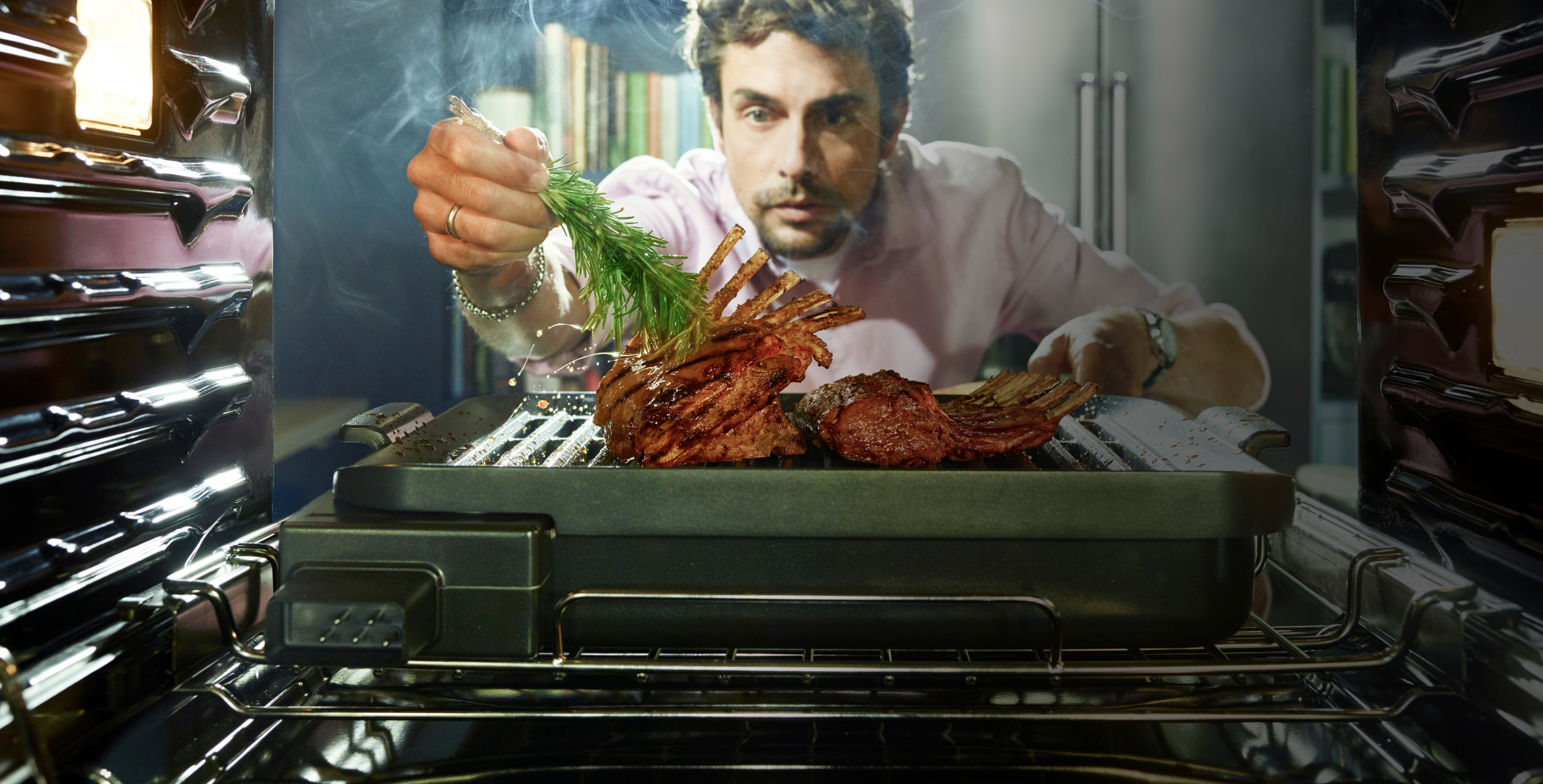 Man brushing a delectable roast with fresh rosemary, just coming out of the oven.