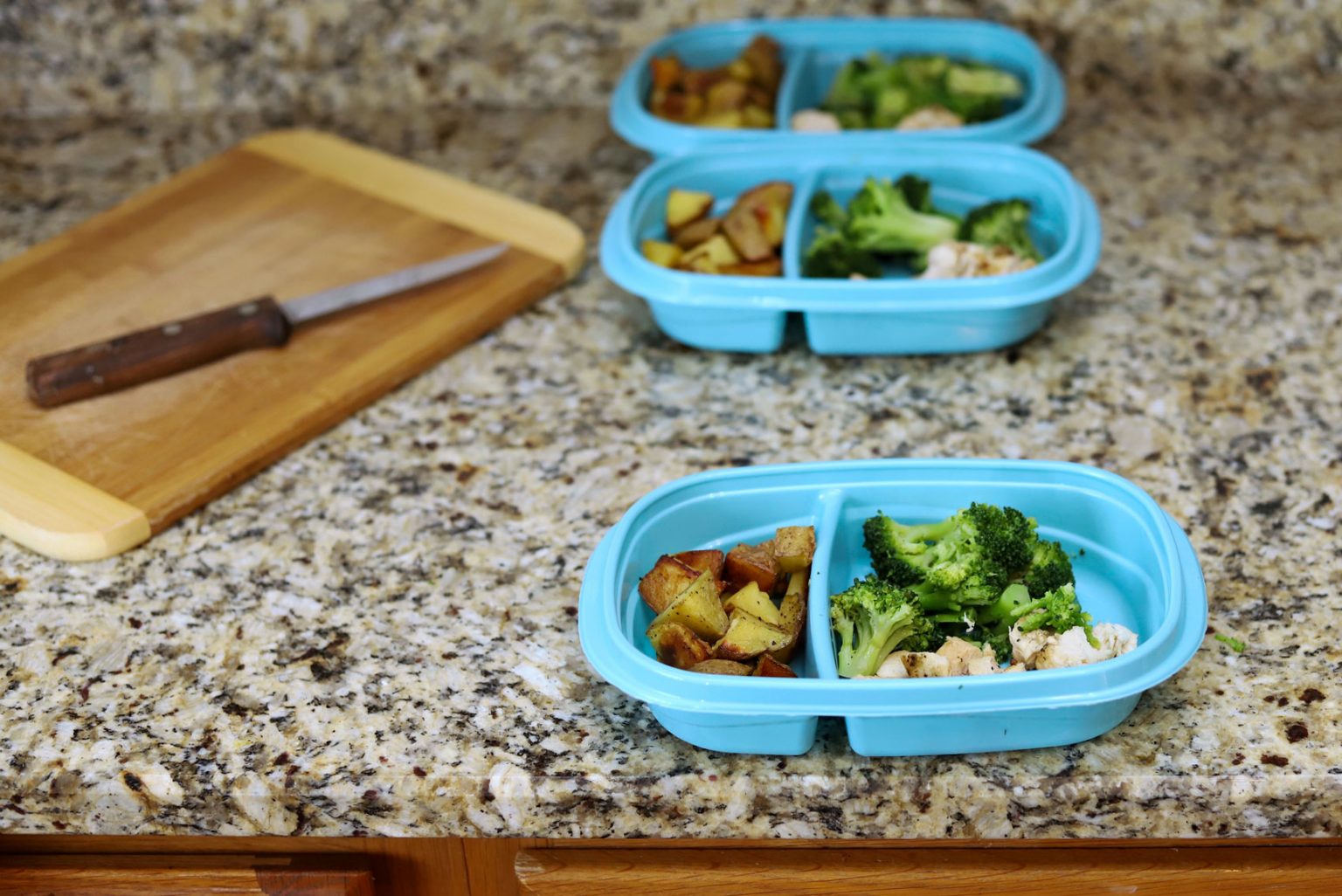 Three blue contaners being sorted for meal prepping.