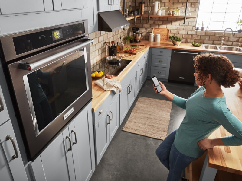 Person controlling smart appliance settings through app on phone