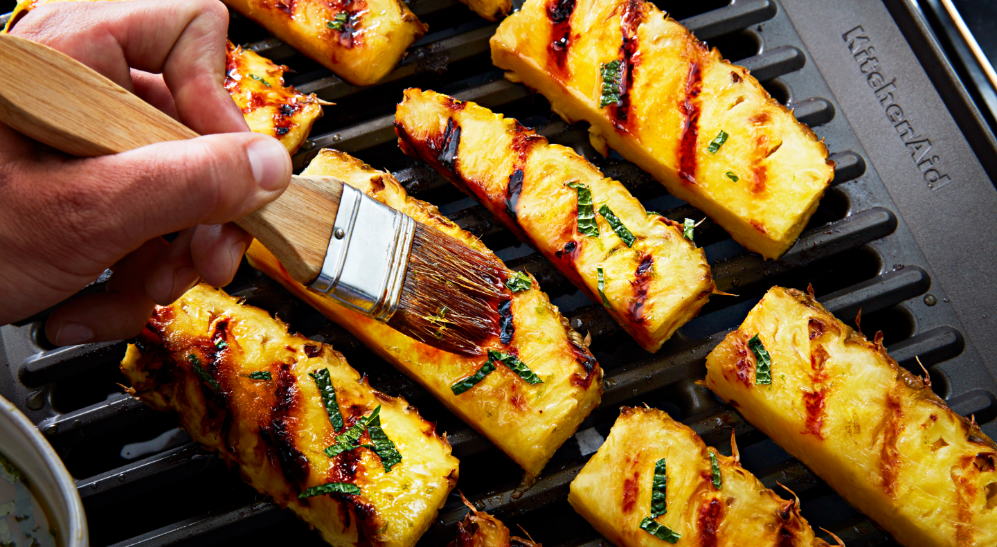 Hand dressing grilled pineapples with a pastry brush