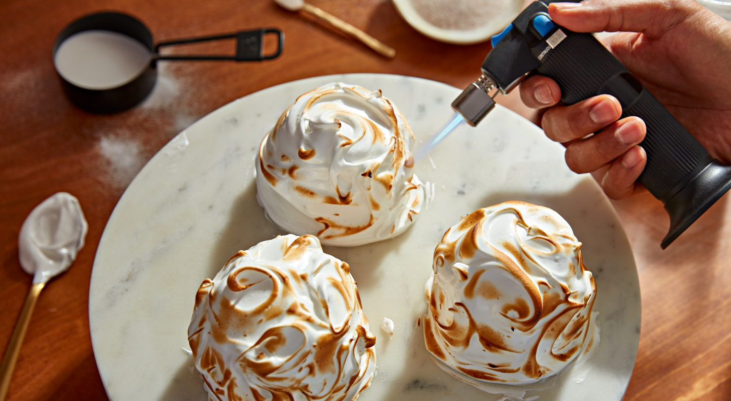 Hand using a culinary torch to caramelize ganache