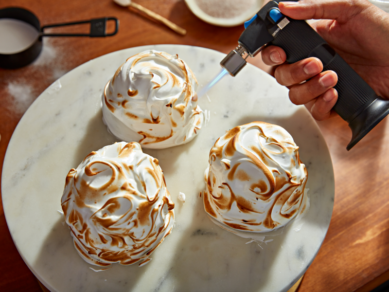 Hand using a culinary torch to caramelize ganache