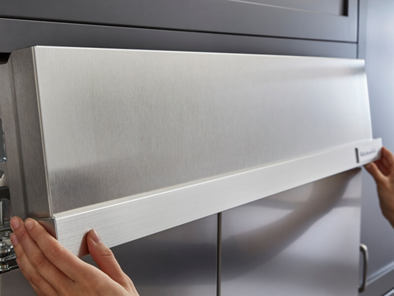 Hands installing parts of a KitchenAid® refrigerator