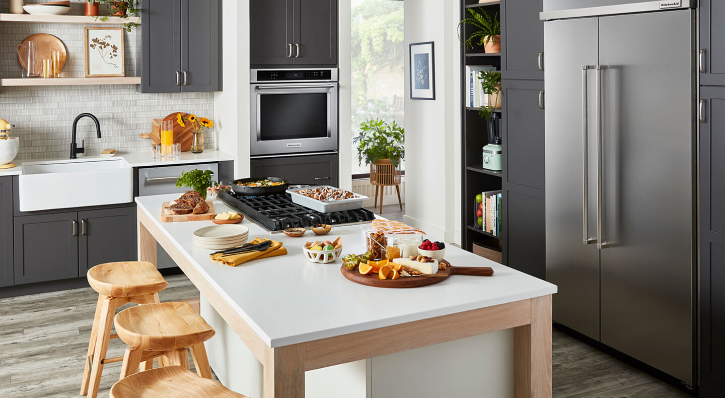 A stylish, modern kitchen filled with KitchenAid® appliances and prepared dishes on the island