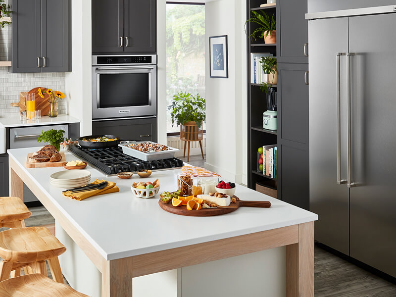 A stylish, modern kitchen filled with KitchenAid® appliances and prepared dishes on the island