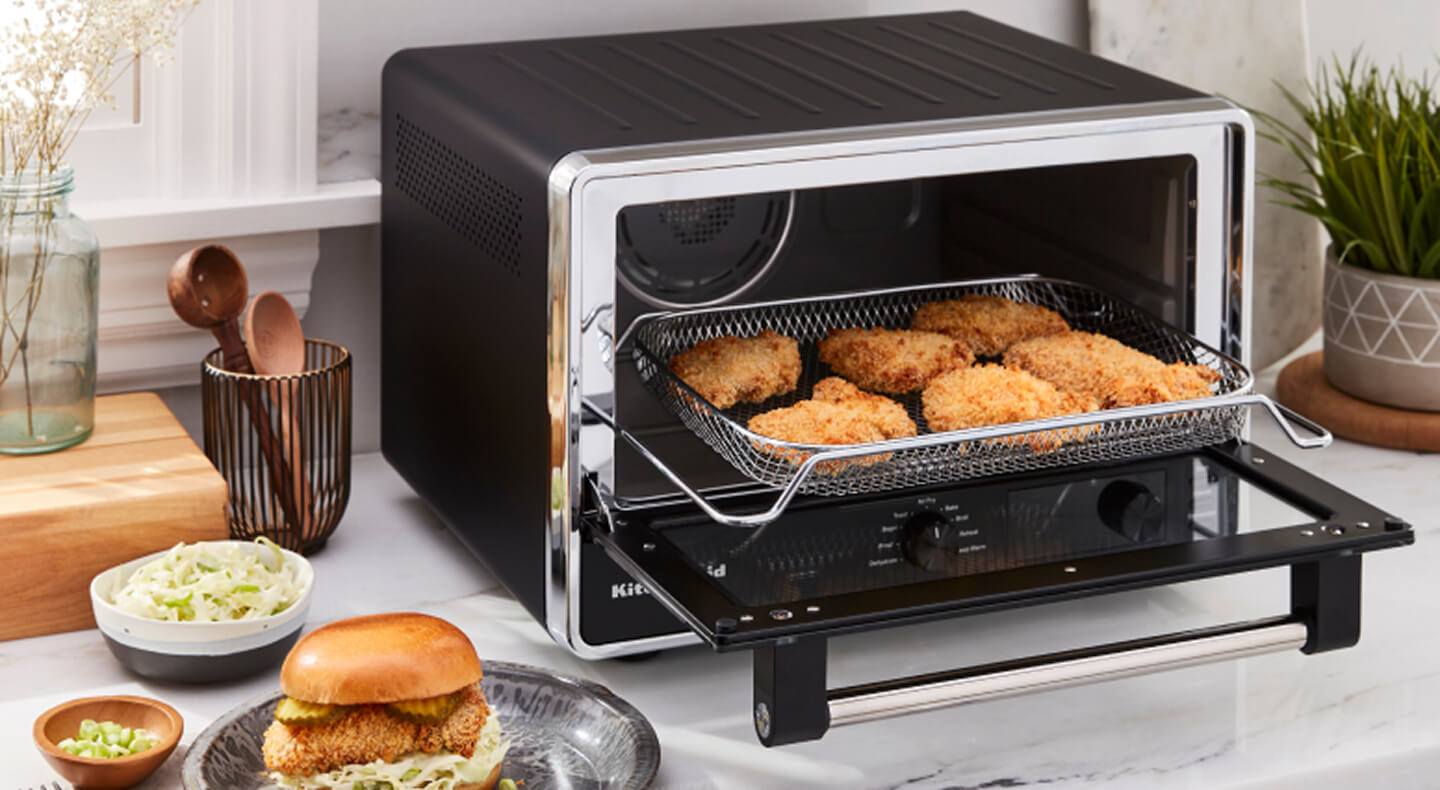 A KitchenAid® countertop oven preparing chicken patties for sandwiches