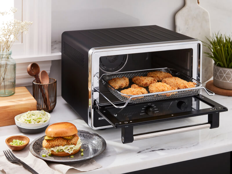A KitchenAid® countertop oven preparing chicken patties for sandwiches