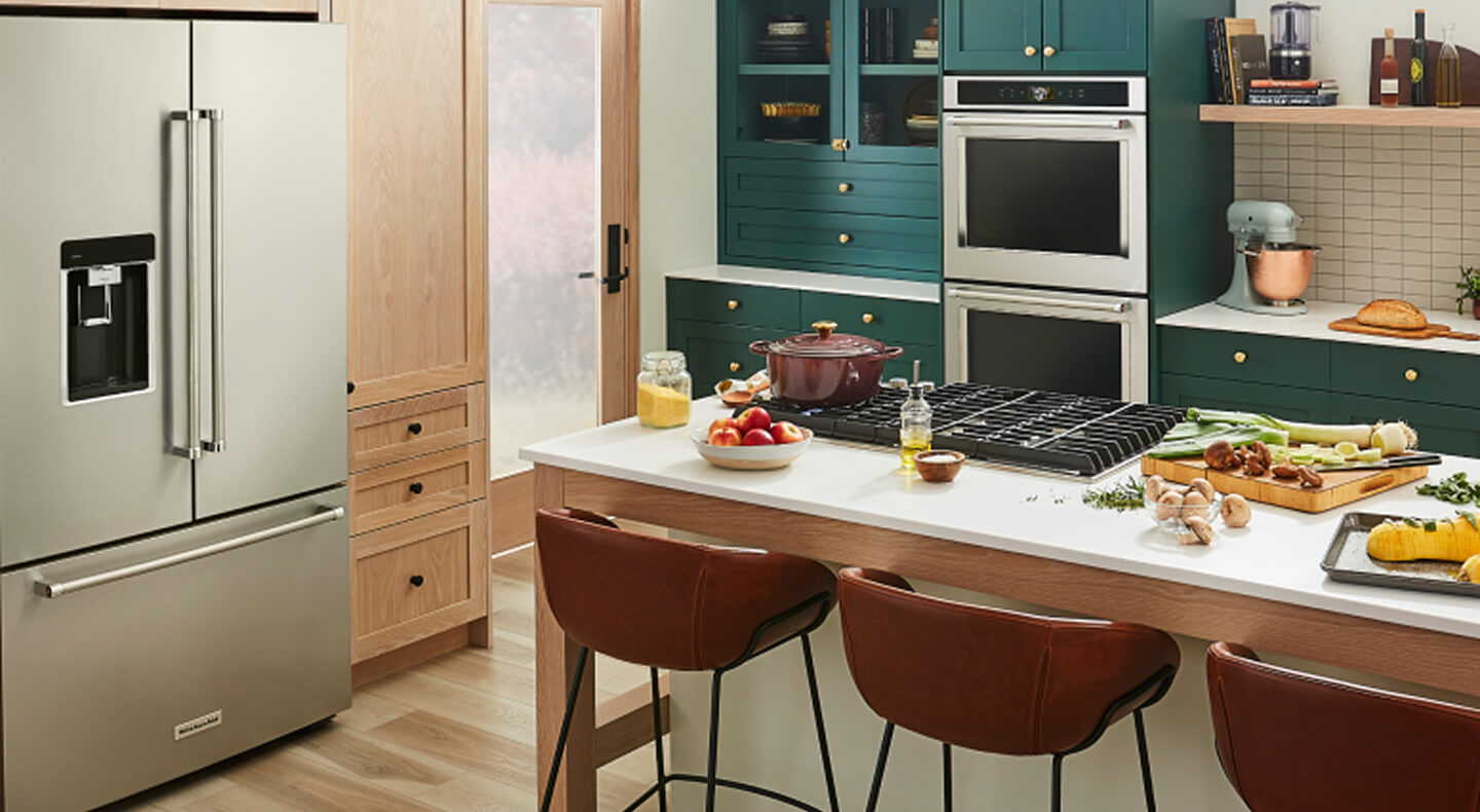 A trendy kitchen with teal cabinetry and a suite of KitchenAid® appliances