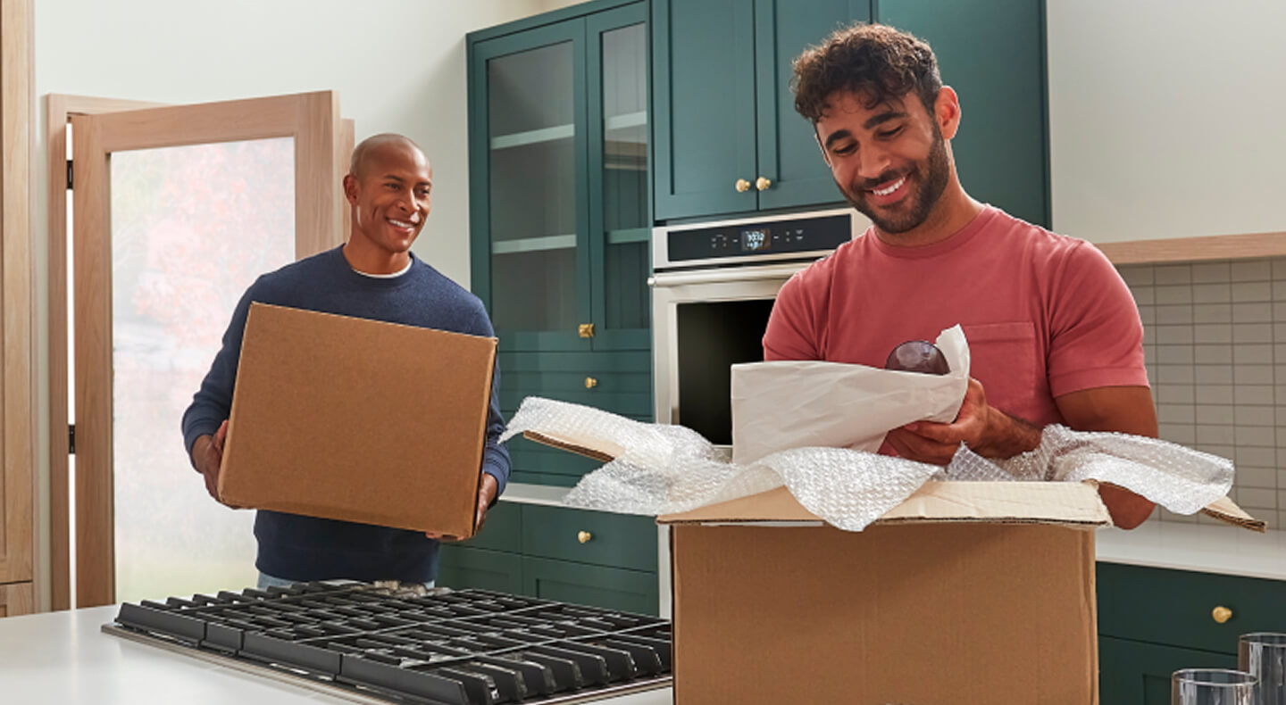 Two men moving and unpacking boxes in a remodeled kitchen