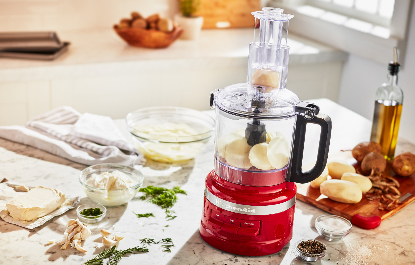 Potatoes in food processor surrounded by ingredients