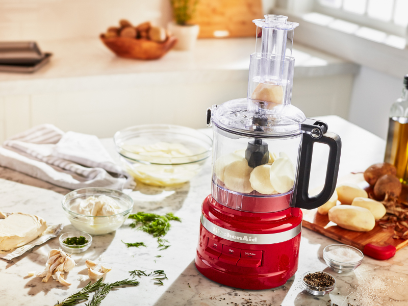 Potatoes in food processor surrounded by ingredients