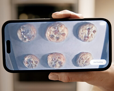 Person monitoring cookies baking from camera feed on their smartphone