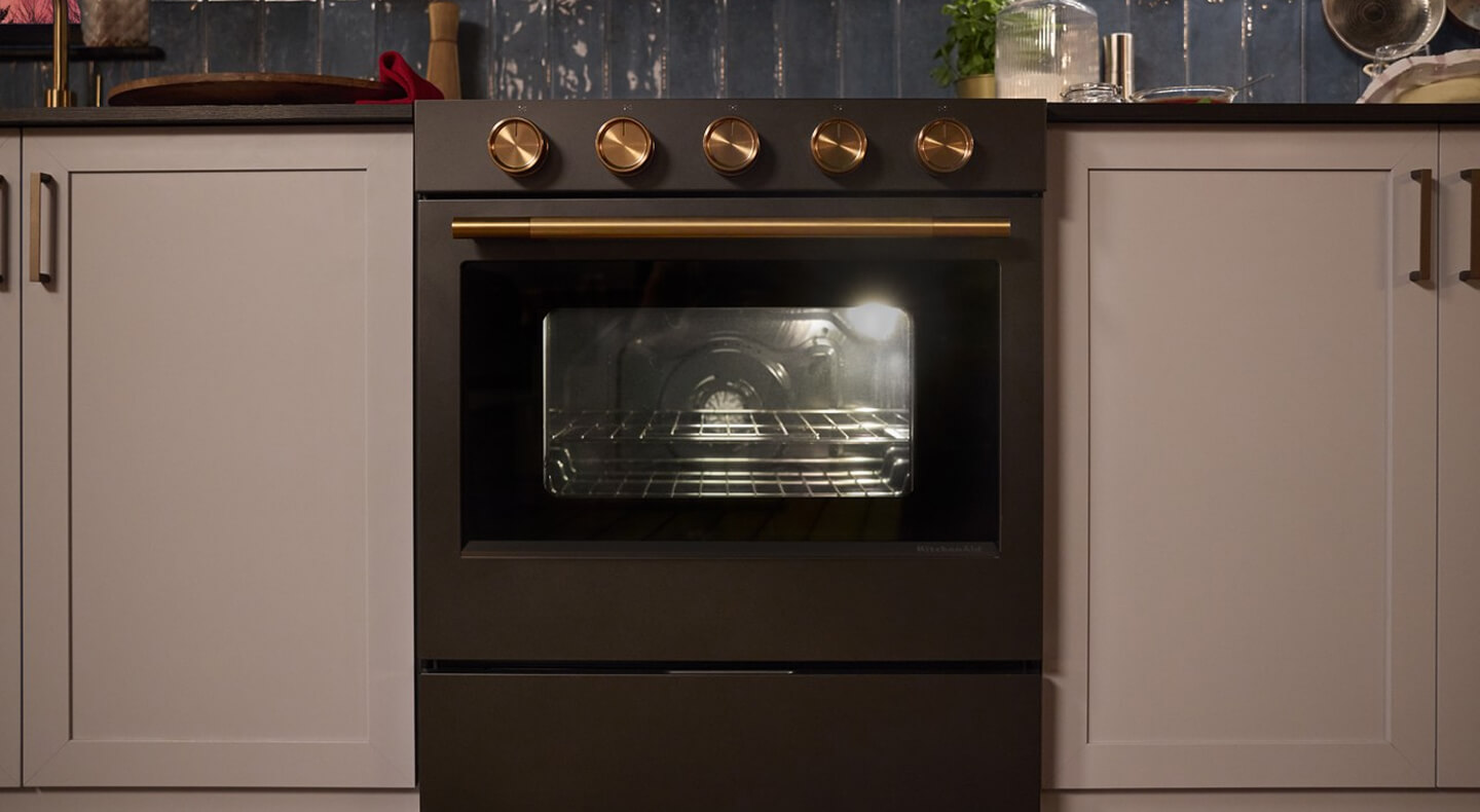 Juniper KitchenAid® range with bronze hardware and a light on in the oven