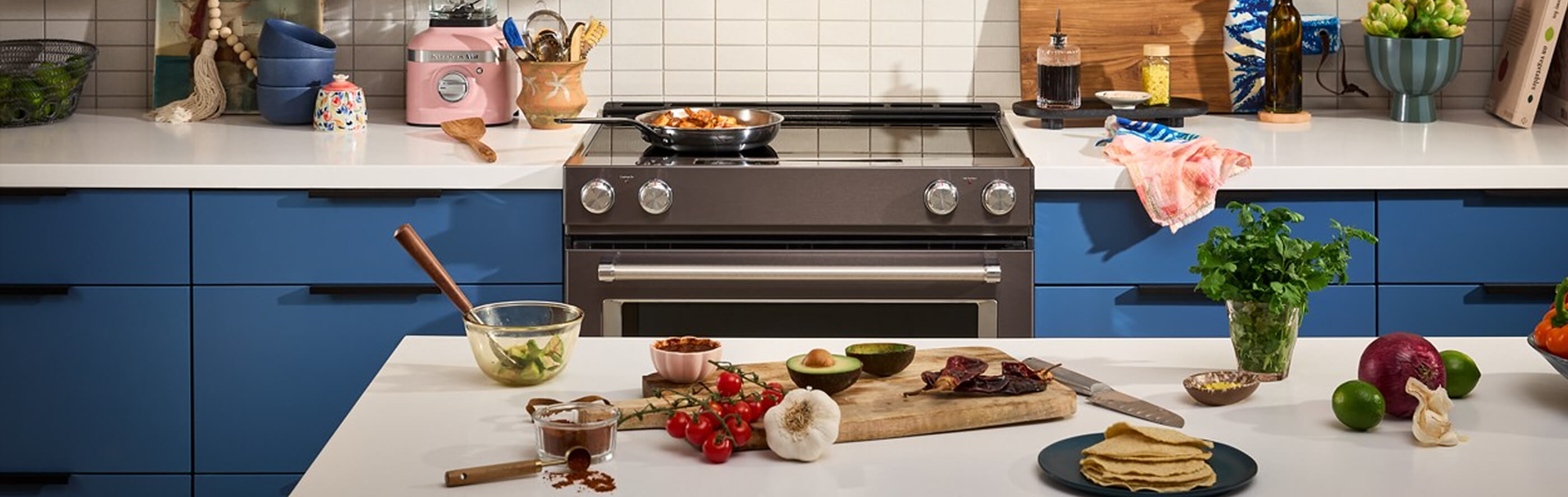 KitchenAid® over-the range microwave and electric range in brown and blue cabinetry
