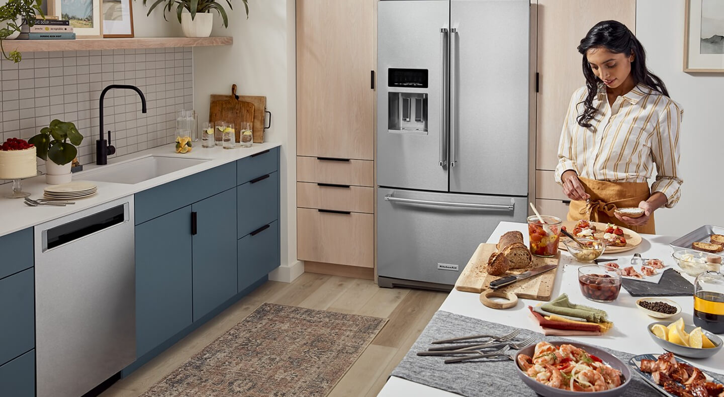 Person prepping food on a kitchen island in front of French door refrigerator