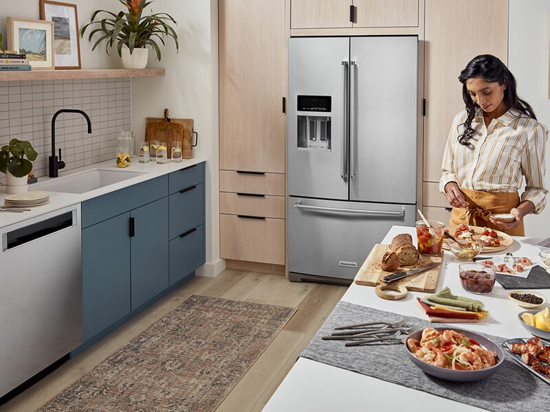 Person prepping food on a kitchen island in front of French door refrigerator