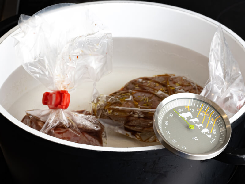 Bagged food with a thermometer in a pot of water