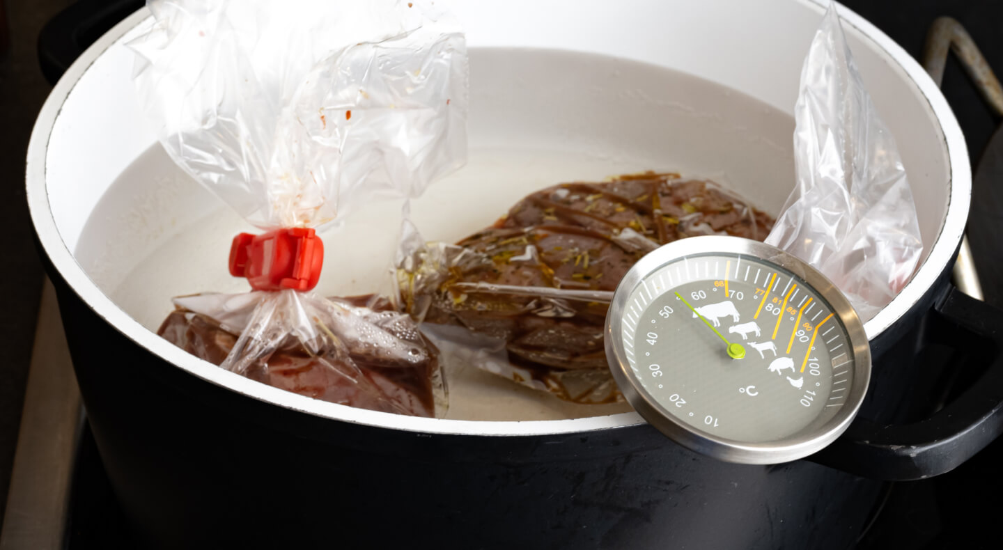 Bagged food with a thermometer in a pot of water