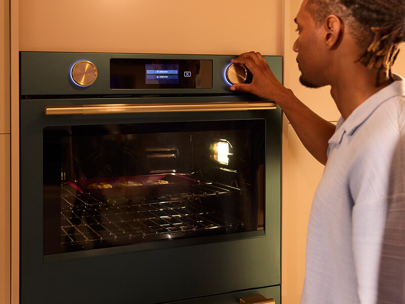 A person operating their wall oven control panel