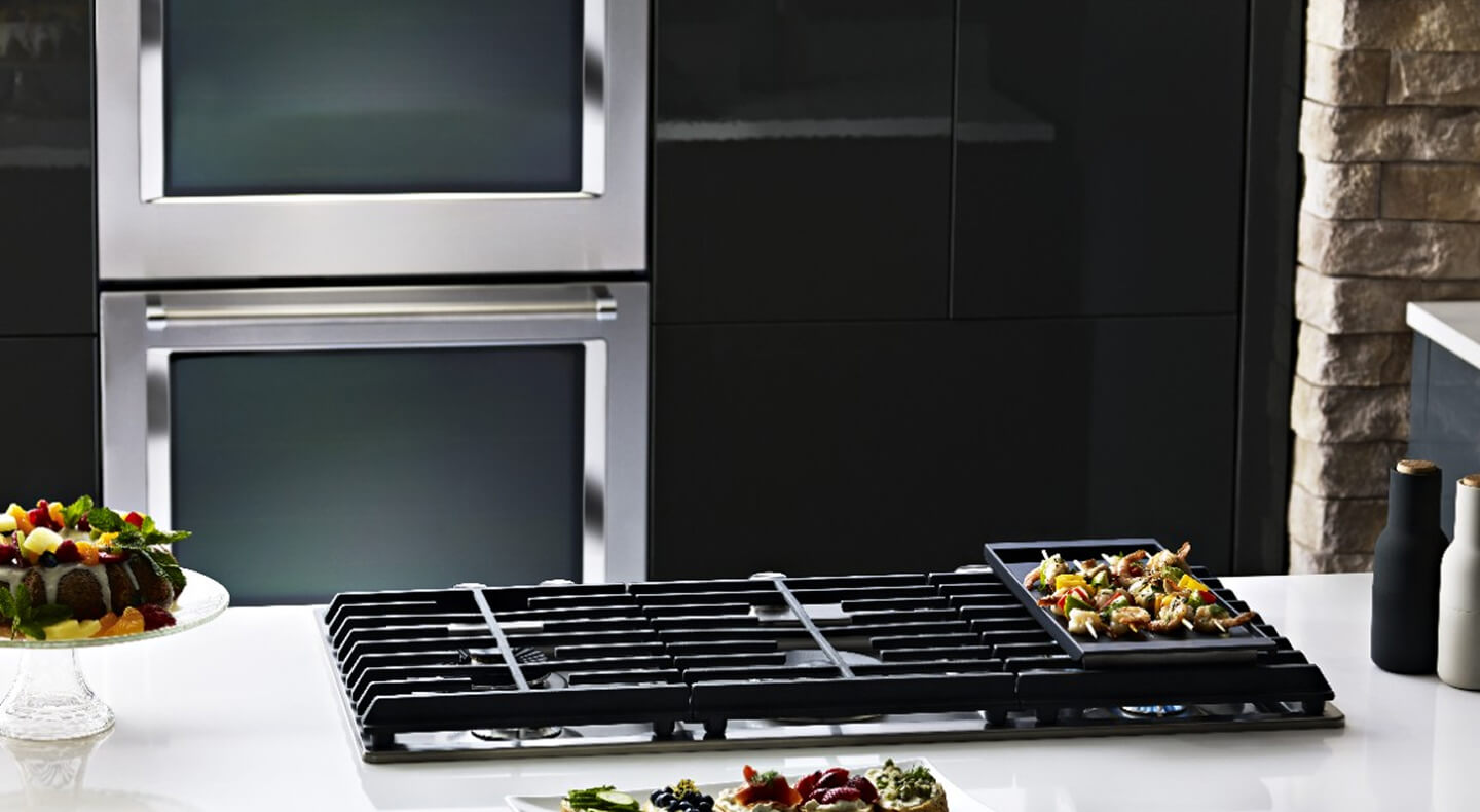 A KitchenAid® gas cooktop with a double KitchenAid® wall oven in the background