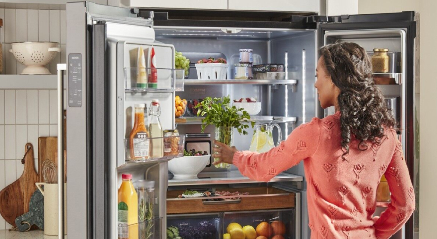 Person loading fresh herbs into a KitchenAid® French door refrigerator
