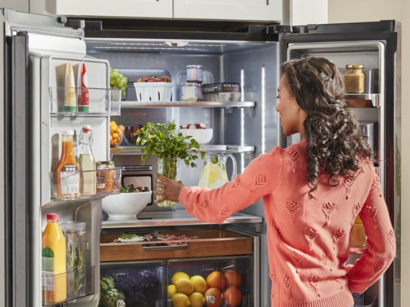 Person loading fresh herbs into a KitchenAid® French door refrigerator