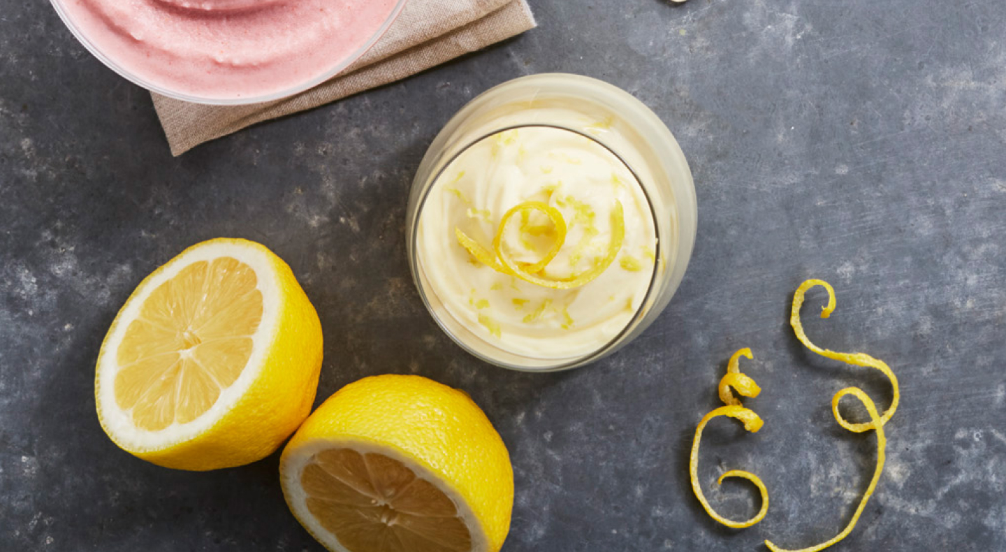 Parfait with lemon peels and whole lemons next to it.