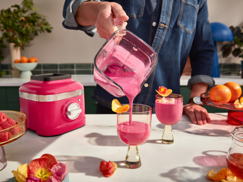  A man pouring a freshly made smoothie from a KitchenAid® blender pitcher into a glass.