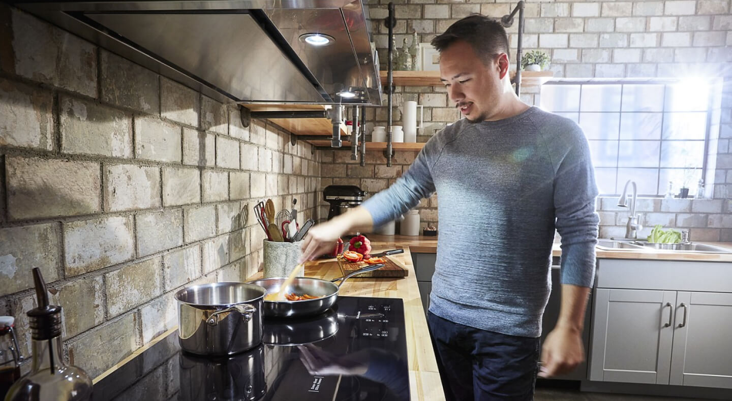 Person sautéing food on a KitchenAid® induction cooktop