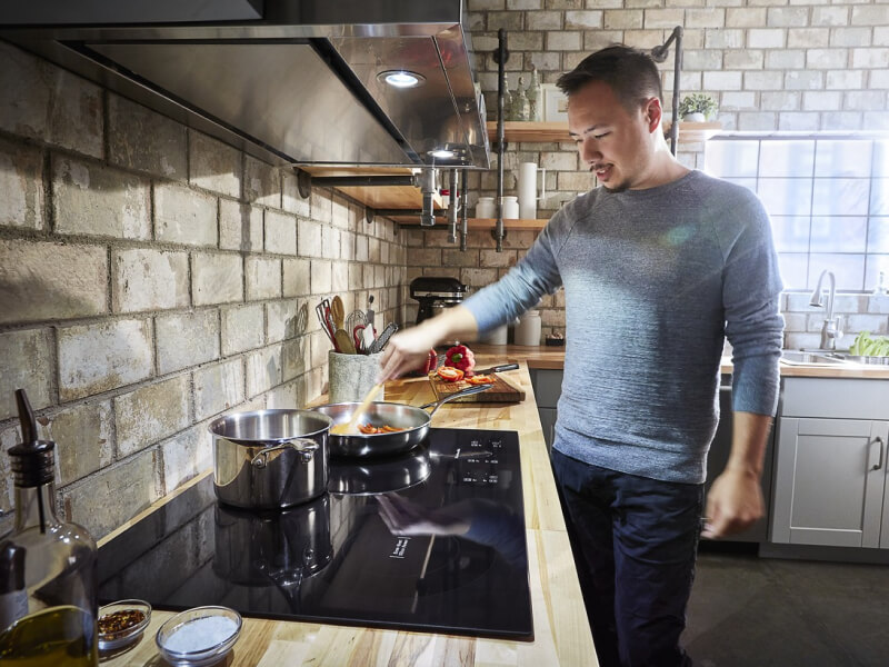 Person sautéing food on a KitchenAid® induction cooktop