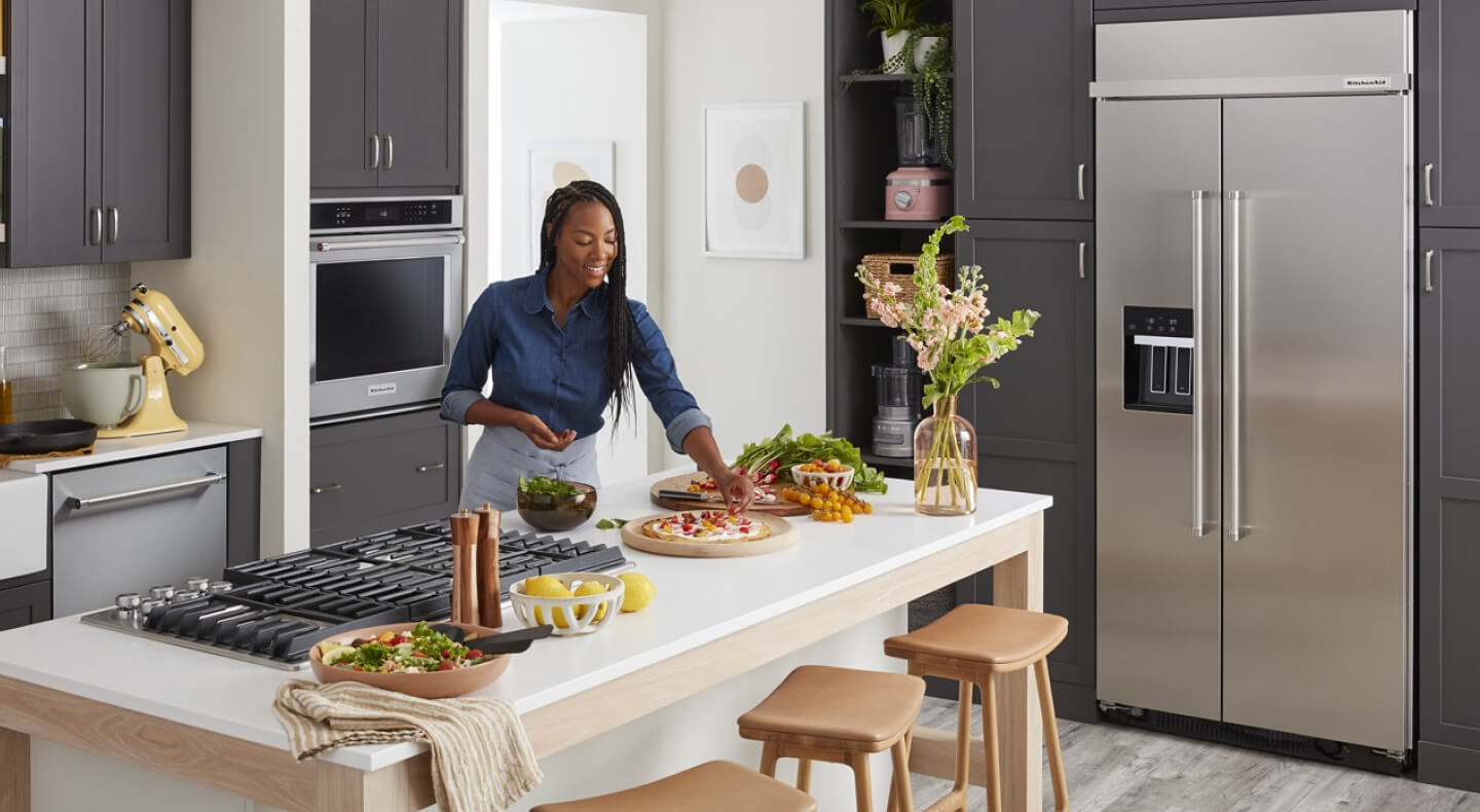 Person garnishing dishes on a kitchen island