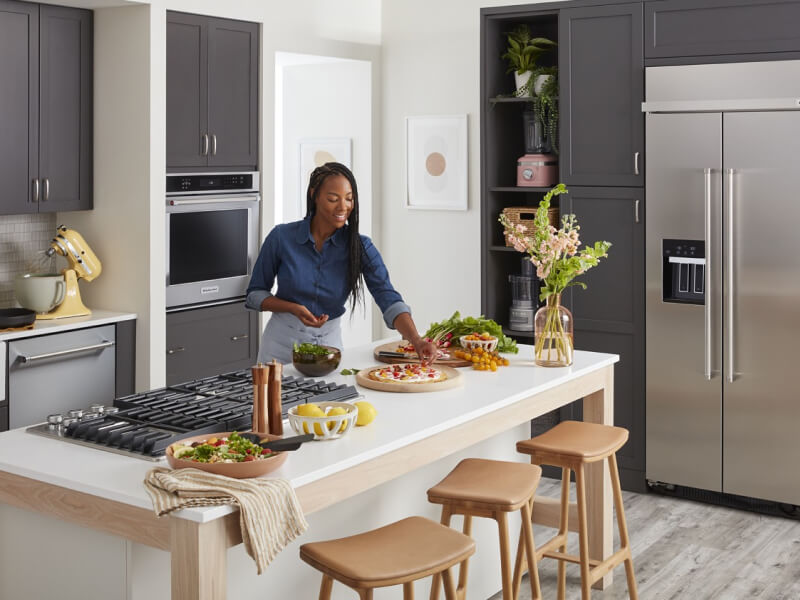 Person garnishing dishes on a kitchen island