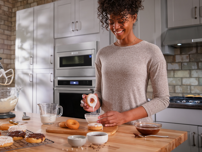 Person dipping a donut in homemade frosting