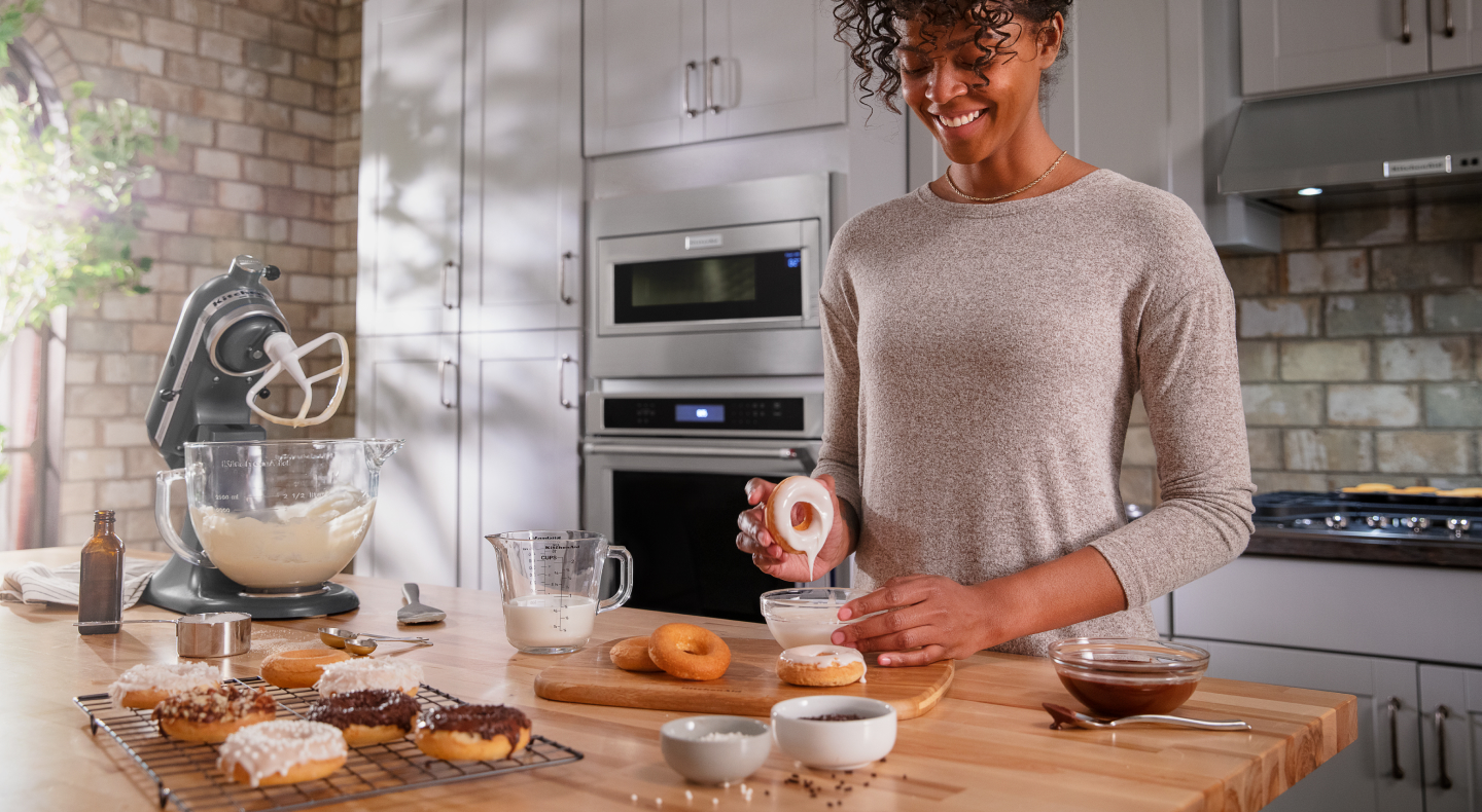 Person dipping a donut in homemade frosting