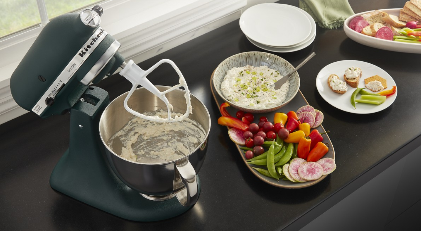 Black KitchenAid brand stand mixer with a flat beater making dip