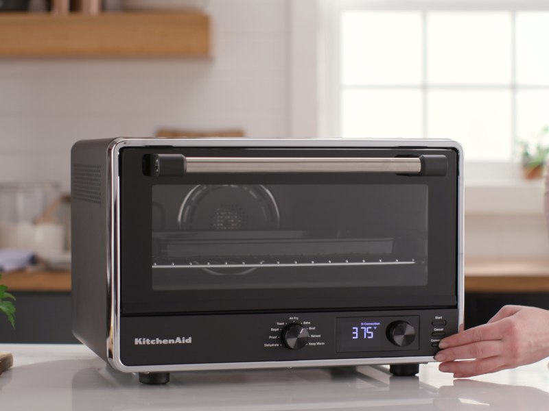 Person setting controls on a KitchenAid® countertop oven