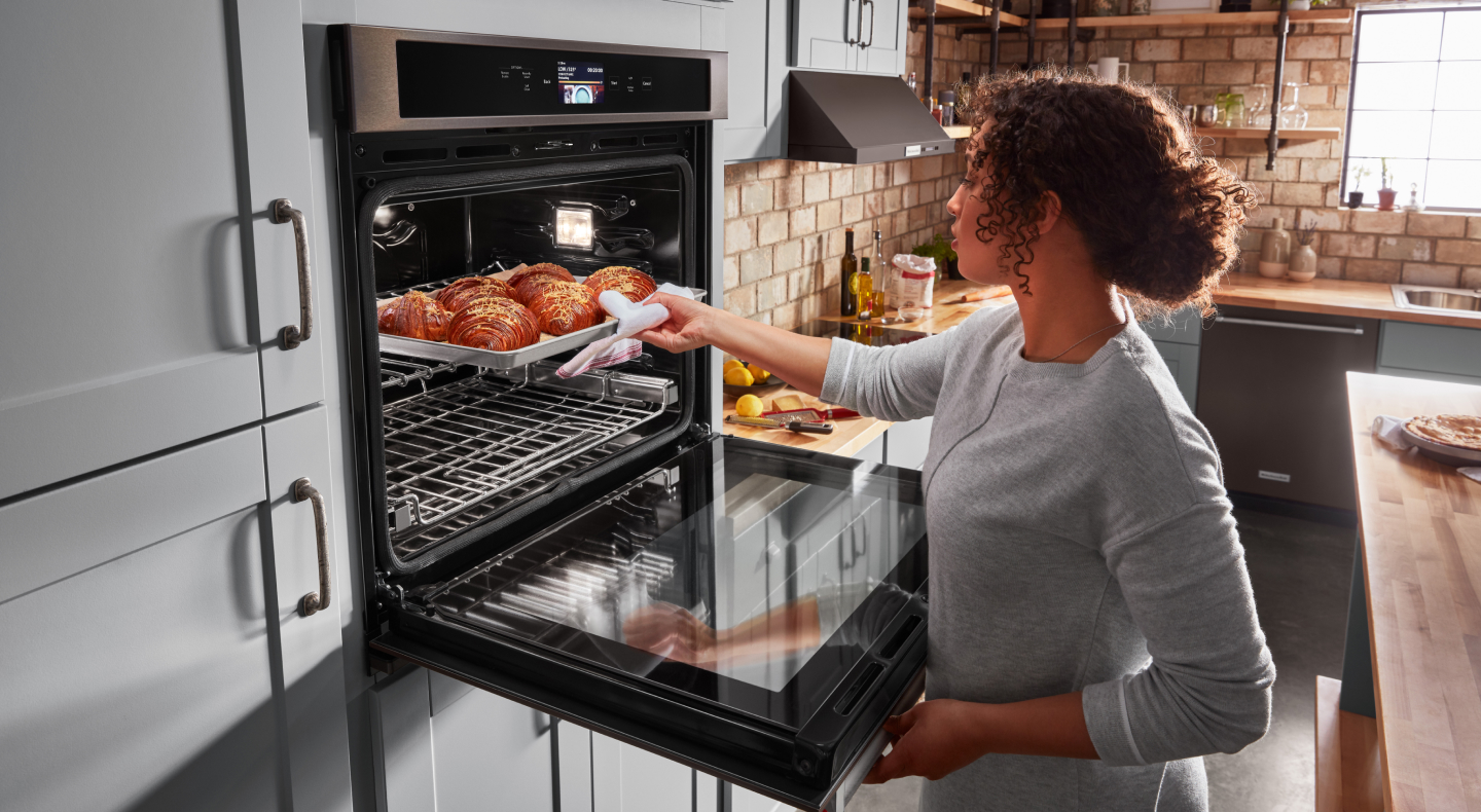 Person pulling pastries out of an oven