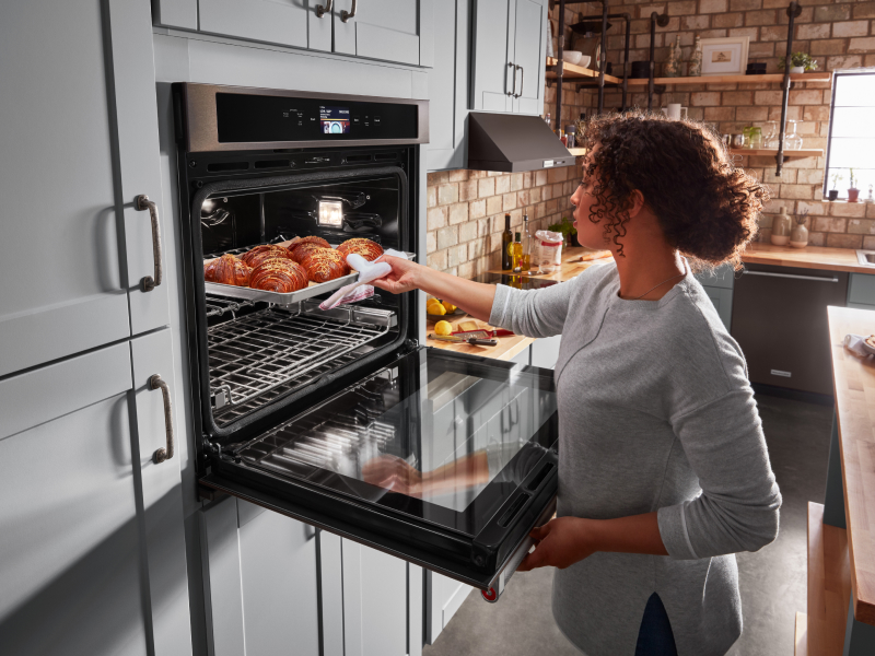 Person pulling pastries out of an oven