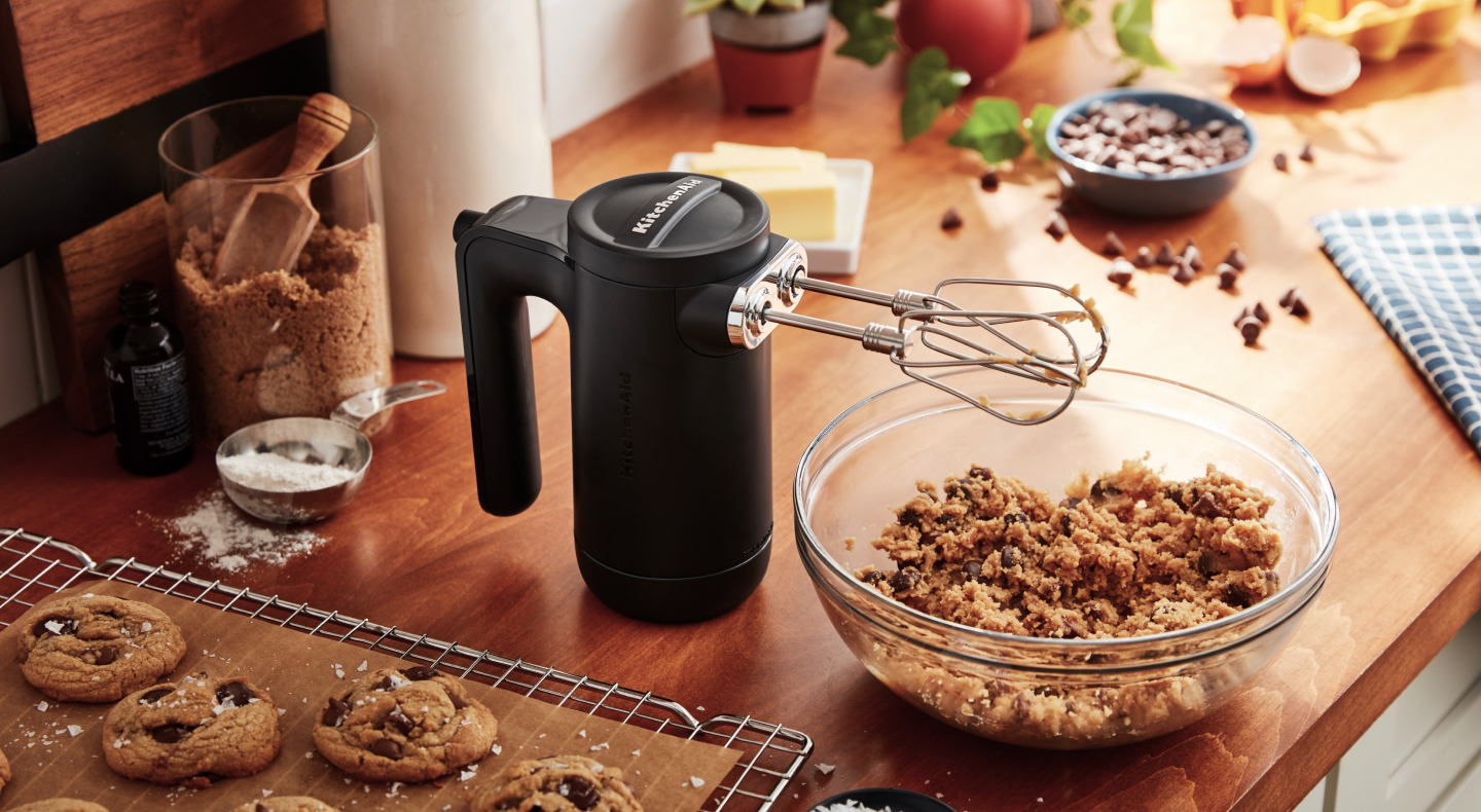 Black KitchenAid® hand mixer with beaters over cookie dough