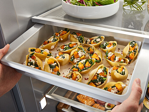 Person removing refrigerator sliding tray full of hors de’voures