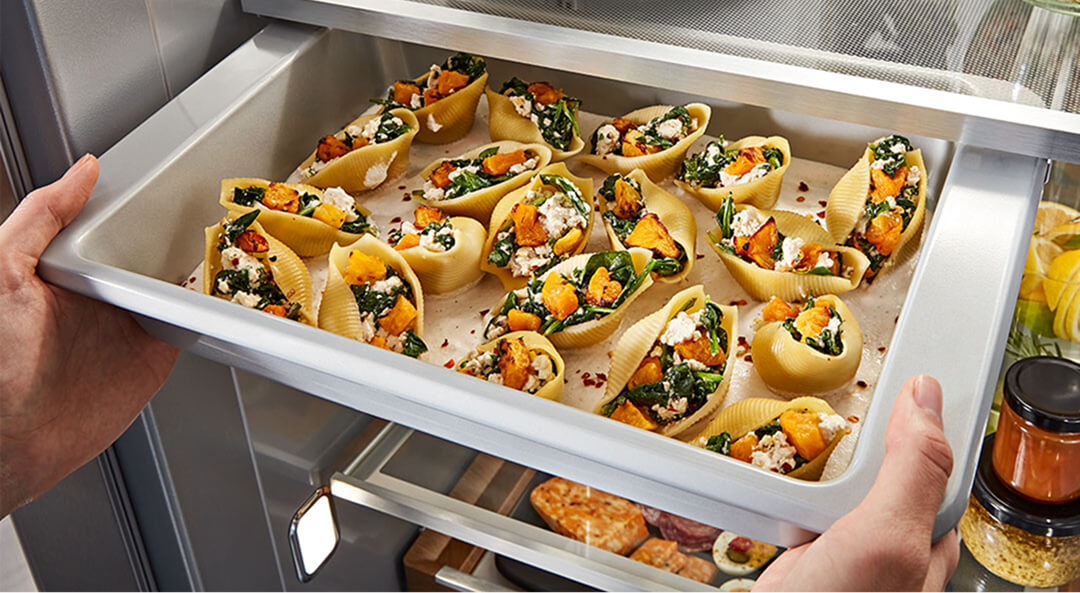 Person removing refrigerator sliding tray full of hors d'oeuvres