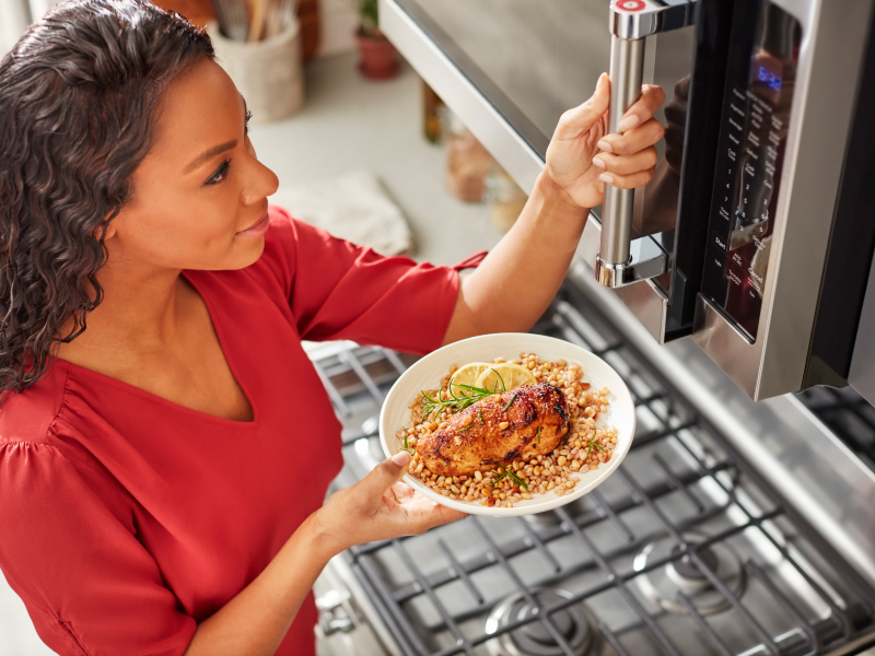 Person preparing heat up food in a KitchenAid® stainless steel microwave