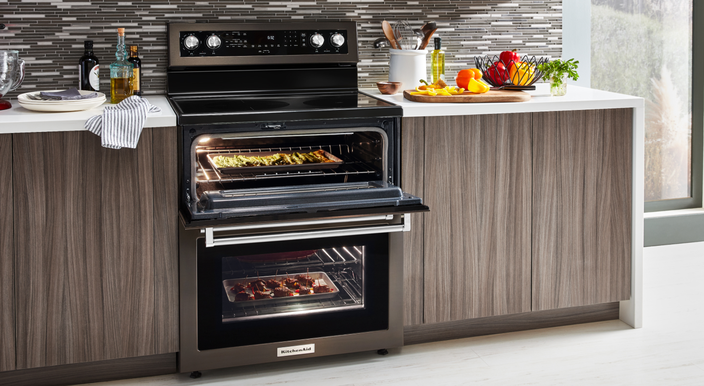 A slide-in double oven range with various dishes cooking inside