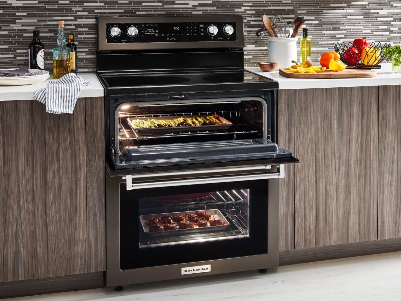 A slide-in double oven range with various dishes cooking inside