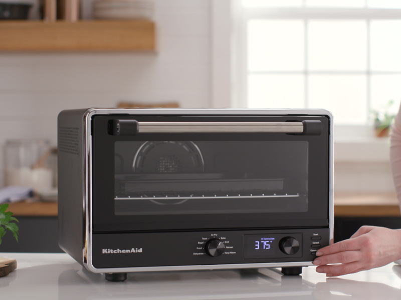 Person pressing setting on KitchenAid® countertop oven